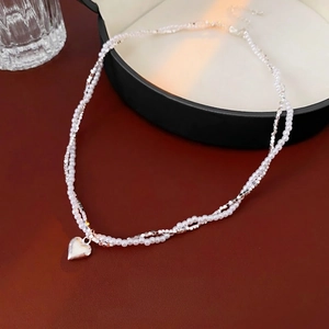 Double-layered necklace with silver heart pendant and white pearls on jewelry box
