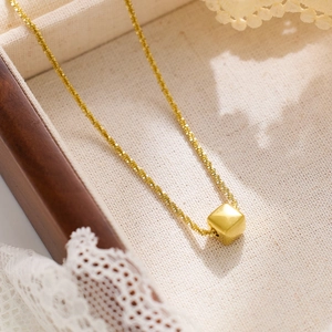 Macro shot of gold-plated square pendant necklace on elegant linen and lace background
