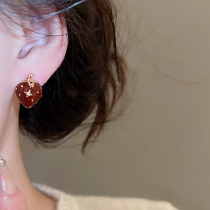 Primo piano di orecchino a fragola in smalto rosso con piccolo zircone centrale