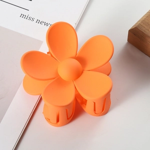 Close-up of bright orange flower hair claw clip with a matte finish and secure grip teeth