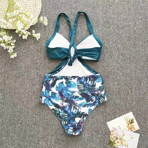 Detailed view of cutout one-piece swimsuit with tropical leaf print and crossover neck straps