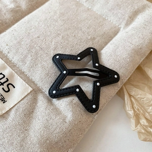 Detailed macro view of star shaped hair clip with white polka dots on beige fabric