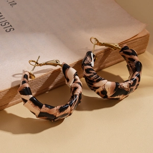 Detail shot of leopard print fabric wrapped hoop earrings with gold metal accents