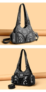 Detail showing soft black leather texture and flower-shaped zipper heads on the bag