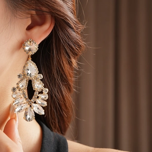 Close-up of elegant gold drop tassel earrings with rhinestones worn by a model