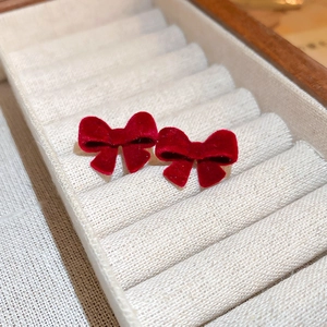 Close-up of red velvet bow stud earrings with silver needles in a jewelry box storage