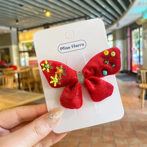 Détail d'un nœud papillon de Noël en velours rouge avec perles colorées et flocons