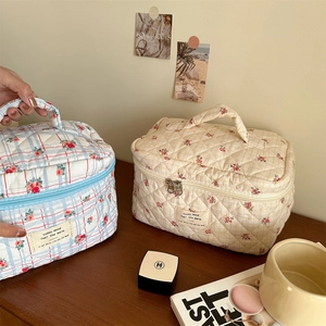 Detail view of floral quilted cotton makeup bags in blue and beige checkered patterns