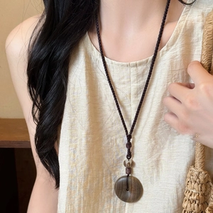 Collar étnico retro con colgante de madera y cordón tejido sobre top de lino