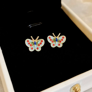 Détail macro de boucles d'oreilles papillon dorées avec émail bleu dans un écrin à bijoux