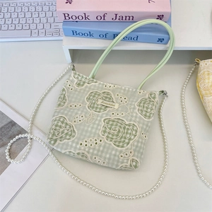 Détail d'un sac à main brodé en dentelle vert menthe avec chaîne en perles et fleurs