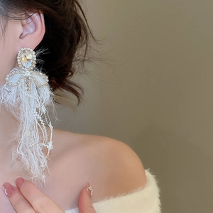 Elegantly styled bow tassel earrings with sparkling rhinestones worn by a model