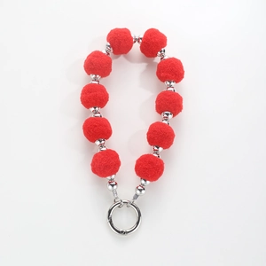 Detail of red plush pompom wristlet with metallic silver beads and spring ring clasp