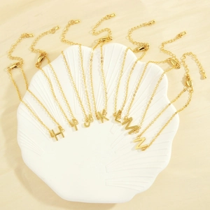 18K gold plated minimalist alphabet bracelets featuring letters H to N on a shell tray