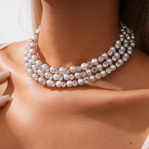 Close-up of triple-layer pearl necklace with sparkling rhinestone accents on neck