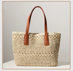 Detailed view of woven straw texture and premium brown leather handles on a summer tote bag