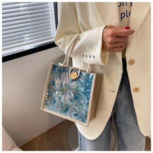 Blue floral linen tote bag with rope handles and wood button detail shown on model