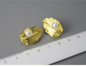 Detailed size measurement of golden leaf pearl earrings shown against a metric scale ruler