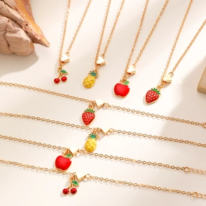 Dettaglio delle collane dorate con ciondoli smaltati a forma di ciliegia e mela