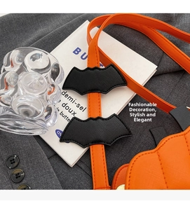 Detail of orange pumpkin bag featuring bat patches and cross-grain leather strap