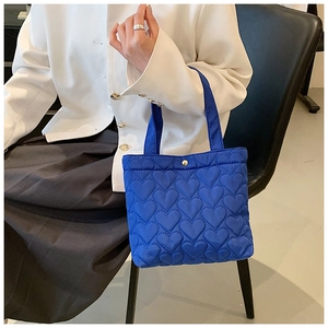 Detail of royal blue heart-quilted oxford fabric tote bag shown on a model