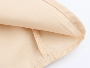 Nahaufnahme der beigen Stoffstruktur mit hochwertigen Nähten für das Sommerkleid