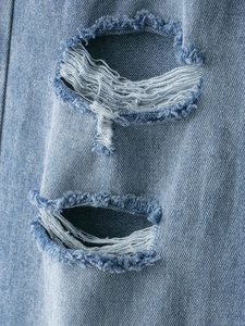 Dettaglio macro del denim azzurro con strappi alla moda e bordi sfrangiati rifiniti