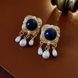Vintage royal blue gemstone earrings with pearl pendants on brown leather background
