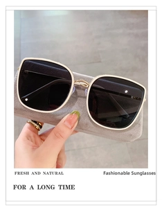 Close-up of white oversized sunglasses with golden metal temples and dark gray lenses