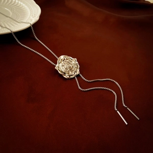 Detail showing metallic 3D rose pendant and adjustable silver chain on velvet