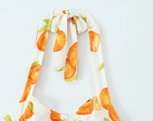 Detailansicht des Neckholder-Ausschnitts mit Orangendruck und Schleife am Leinenkleid