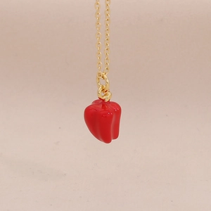 Detailopname van een rode chilipeper hanger aan een elegante gouden schakelketting