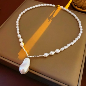 Macro shot of irregular baroque pearl pendant on a fine seed pearl chain with silver beads
