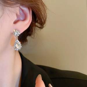 Detail of elegant silver V-shaped earrings with diamond tassels on a model