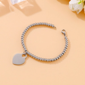 Macro detail of silver beaded stainless steel bracelet with a heart shaped pendant charm