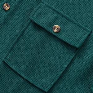 Detalle de punto de gofre verde oscuro con bolsillo con solapa y botón de madera marrón