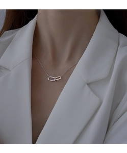 Dettaglio della collana d'argento con due pendenti rettangolari indossata su un blazer bianco