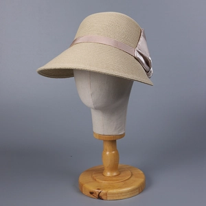 Close-up of woven straw sun hat with elegant champagne satin bow on mannequin