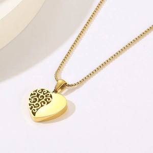 Détail macro d'un pendentif cœur doré avec motif floral ajouré et finition polie brillante