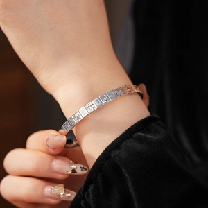 Detail of silver metal cuff bracelet featuring traditional Chinese Mahjong motifs and characters