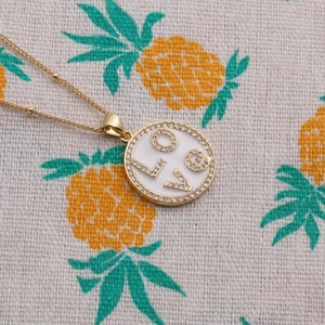 Collier doré avec pendentif rond en émail blanc et lettrage LOVE en zircon