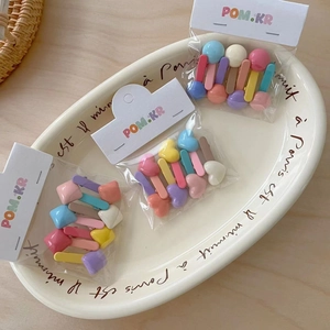 Candy colored matte hair clips set in heart and geometric shapes on a white tray