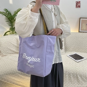 Detail of purple canvas tote bag with Bonjour magic text and plaid shoulder strap