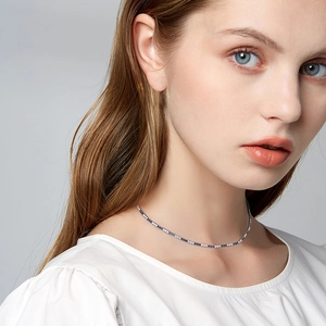 Collier élégant en zircone bleu et blanc ajustable sur mannequin avec fond gris clair