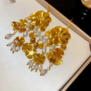 Detailaufnahme der Vintage-Goldblumen-Ohrringe mit Perlenquasten auf einer Schmuckbox