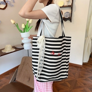 Detail of striped canvas tote with red embroidery and white lace ribbon decoration