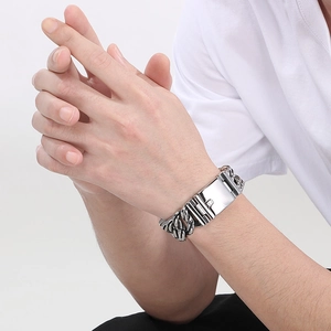 Close-up of a silver chunky Cuban chain bracelet with an engraved metal plate on wrist