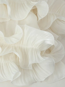 Macro view of white layered ruffles and sheer chiffon fabric on a summer dress