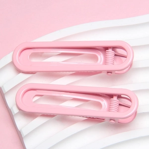 Minimalist 6cm pink U-shaped rectangle hair clips set on a decorative white wave board