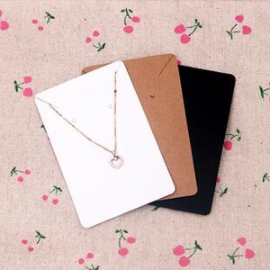 Detailed view of white jewelry display card featuring a silver heart pendant necklace